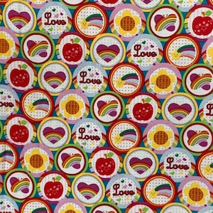 May include: A colorful fabric with a repeating pattern of circles. Each circle features a different design, including a rainbow, a heart, a sunflower, a star, and an apple. The word "Love" appears in some of the circles.