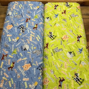 May include: Two rolls of fabric with a repeating pattern of farm animals and sound effects like "moo" and "oink" on blue and green backgrounds. A wooden ruler is at the top.