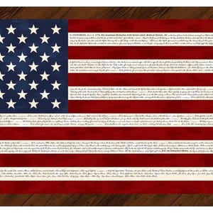 May include: A rectangular artwork featuring the American flag design. The flag has a blue canton with white stars and red and white stripes. The text of the Declaration of Independence is printed on the stripes. The artwork is set against a wooden background.