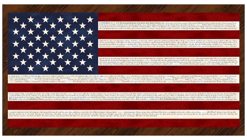 May include: A rectangular artwork featuring the American flag design. The flag has a blue canton with white stars and red and white stripes. The text of the Declaration of Independence is printed on the stripes. The artwork is set against a wooden background.