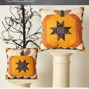May include: Two square throw pillows featuring a pieced pumpkin design with a central dark star motif. The pillows are crafted from orange, cream, and dark brown patterned fabric. Text on the image indicates sizes of 14 inches by 14 inches and 10 inches by 10 inches.