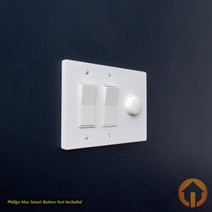 May include: White light switch plate with two toggle switches and a round dimmer knob. The text "Philips Hue Smart Button Not Included" is below the plate.