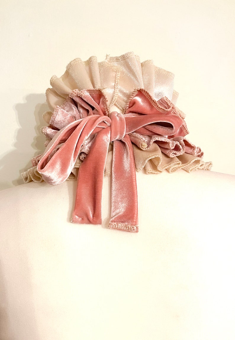 Peut inclure: Un chouchou &agrave; plusieurs couches avec une texture douce et velout&eacute;e. Le chouchou pr&eacute;sente une base beige clair avec des bords fronc&eacute;s, recouverte d'un n&oelig;ud en velours rose poudr&eacute;. Les longues queues fluides du n&oelig;ud ajoutent une touche d'&eacute;l&eacute;gance.