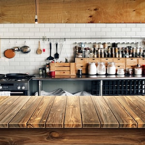 Puede incluir: Una encimera de madera rústica con una cocina en el fondo. La cocina cuenta con azulejos blancos de metro, electrodomésticos de acero inoxidable y armarios de madera llenos de frascos de especias y otros ingredientes.