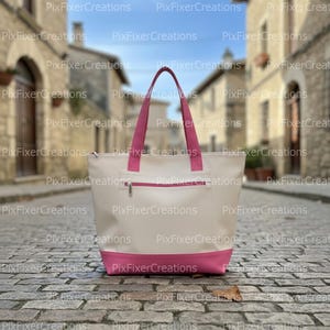 Może przedstawiać: Kremowa torba typu tote z różową podstawą, kieszenią na zamek i pasującymi różowymi uchwytami. Torba wykonana jest z wytrzymałego materiału i jest przeznaczona do przenoszenia przedmiotów. Torba jest pokazana na brukowanej ulicy.