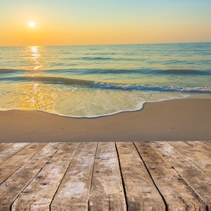 Peut inclure: Un sol en bois avec vue sur une plage de sable et des vagues de l'océan qui se brisent sur le rivage. Le soleil se couche sur l'océan, créant une lueur dorée et chaude.