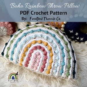 May include: A crocheted rainbow throw pillow with a white background and colorful pom-poms. The pillow is made in a variety of colors, including green, blue, yellow, pink, and red. The pillow is a great addition to any home decor.
