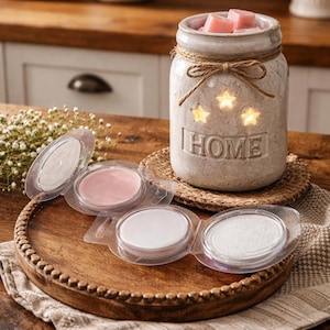 May include: A rustic, beige ceramic wax warmer jar with star cutouts and the word "HOME". The jar is tied with twine and contains pink wax cubes. Several wax melt discs in clear packaging are on a wooden tray.