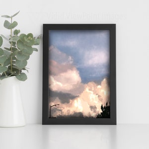 Puede incluir: Una impresión enmarcada en negro de un cielo nublado con una silueta de un poste de luz y árboles en la distancia.