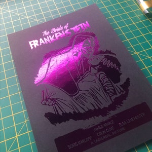 K&ouml;nnte beinhalten: Ein schwarz-wei&szlig;es Poster mit einer pinkfarbenen Folien&uuml;berlagerung. Das Poster zeigt eine schwarz-wei&szlig;e Illustration eines Monsters aus dem Film "Die Braut des Frankenstein". Der Text auf dem Poster lautet "Die Braut des Frankenstein", "Boris Karloff", "James Whale", "Colin Clive", "Elsa Lanchester" und "Ein Universal-Film".