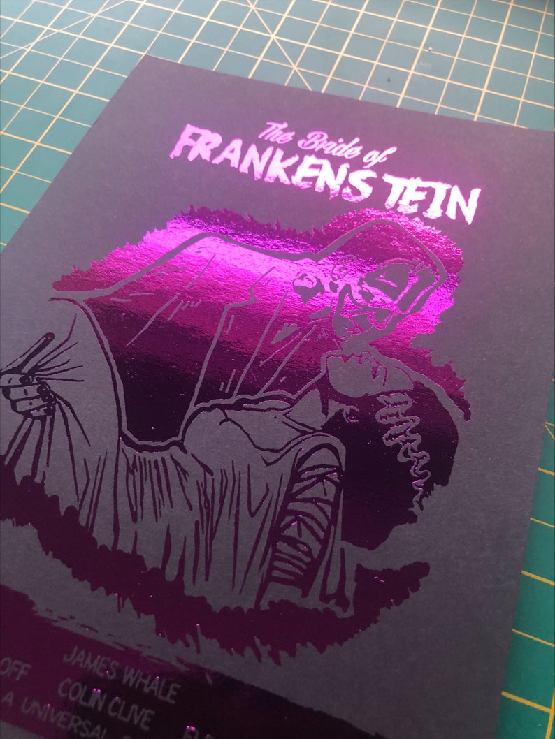 K&ouml;nnte beinhalten: Ein schwarz-wei&szlig;es Poster mit einem pinkfarbenen Foliendruck eines Monsters aus dem Film "Die Braut des Frankenstein". Das Poster zeigt den Text "Die Braut des Frankenstein" und die Namen "James Whale" und "Colin Clive".