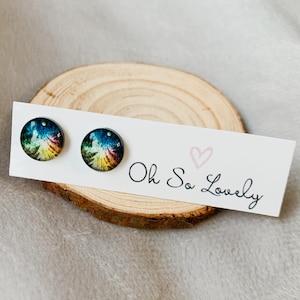 May include: A pair of rainbow galaxy stud earrings on a white card with the text "Oh So Lovely" and a pink heart.