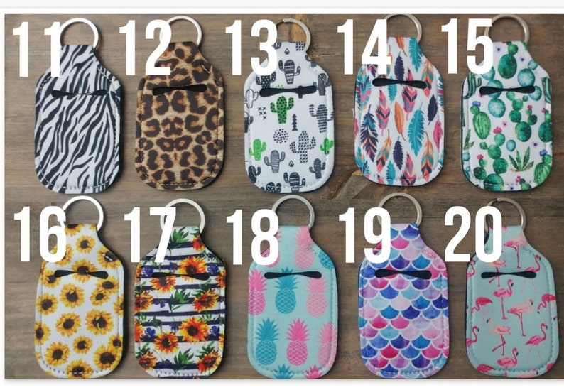 May include: Twenty different hand sanitizer holders with keychains. The holders are made of fabric and feature various patterns, including zebra, leopard, cactus, feathers, sunflowers, pineapples, and flamingos.
