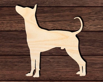 Op de afbeelding: Een houten uitsnijding van een hond in staande positie. De hond kijkt naar rechts en heeft zijn staart opgerold. De uitsnijding is gemaakt van lichtbruin hout en bevindt zich op een donkerbruine houten achtergrond.