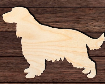 Op de afbeelding: Een houten silhouet van een hond in staande positie. De hond is licht van kleur, met zichtbare houtnerf. De uitsparing staat op een donkerbruin houten oppervlak. De tekst "Signature Cutouts" staat linksonder.