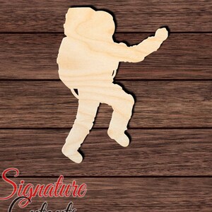 May include: A wooden cutout of an astronaut in a space suit, with arms outstretched, standing on a woodgrain background.