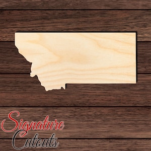 May include: A light-colored, unfinished wooden cutout in the shape of the state of Montana. The piece features a smooth, flat surface with visible natural wood grain patterns throughout, showcasing the distinct geographic outline of the state.