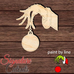 May include: A light-colored wooden cutout featuring a hand with long, thin fingers holding a circular ornament. The design includes a cuff detail on the wrist. Text in the image reads "paint by line" and "Signature Cutouts" along with a small colored graphic.