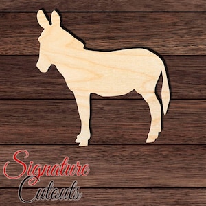 May include: A light-colored wooden cutout in the shape of a donkey standing in profile. The cutout features a smooth, flat surface with visible natural wood grain patterns, depicting the animal with upright ears, a short tail, and four legs.