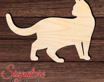 May include: A light-colored wooden cat cutout featuring a smooth, flat surface and a silhouette shape of a standing cat with its tail curved upward. The cutout displays a natural wood grain pattern and is positioned against a dark brown background.