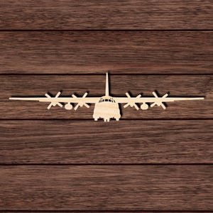 May include: A flat, light-colored wooden cutout of a four-engine turboprop military transport aircraft. The silhouette shows the front view of the plane with a central fuselage, long wings, four propellers, and a vertical stabilizer extending upward.