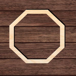 May include: A light-colored, unfinished wooden cutout in the shape of an octagon. The frame features a flat, smooth surface with a natural wood grain texture and eight equal sides, forming a geometric octagonal border with an open center.