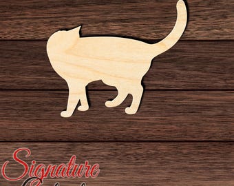 May include: A flat, light-colored wooden cutout in the shape of a cat standing in profile with its tail curved upward. The surface shows a natural wood grain pattern. The cutout is positioned against a dark brown horizontal wood plank background.