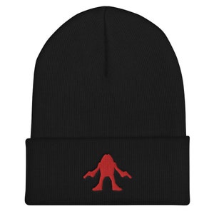 Op de afbeelding: Zwarte beanie met een rood geborduurd monsterontwerp.