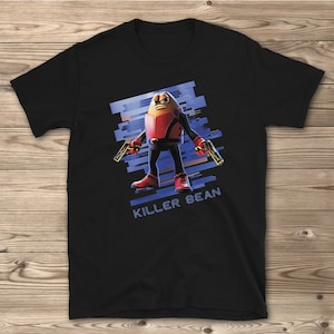 May include: Black t-shirt with a graphic of a bean-shaped character holding two guns. The character is wearing a red and black suit and has a blue background with the text "Killer Bean".