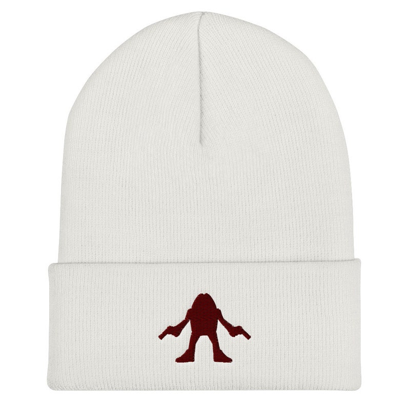 May include: White knit beanie with a red embroidered silhouette of a creature with two guns.