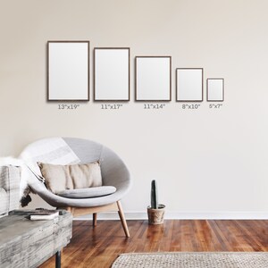 May include: Five framed pictures of different sizes hanging on a beige wall. The frames are brown wood and the pictures are blank. The frames are 13 inches by 19 inches, 11 inches by 17 inches, 11 inches by 14 inches, 8 inches by 10 inches, and 5 inches by 7 inches.