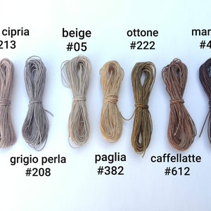 K&ouml;nnte beinhalten: Acht Spulen mit naturfarbenen Garnen, angeordnet in zwei Reihen zu vieren. Die Garnfarben sind: rosa cipria #213, beige #05, ottone #222, marrone #496, grigio perla #208, paglia #382, caffellatte #612.