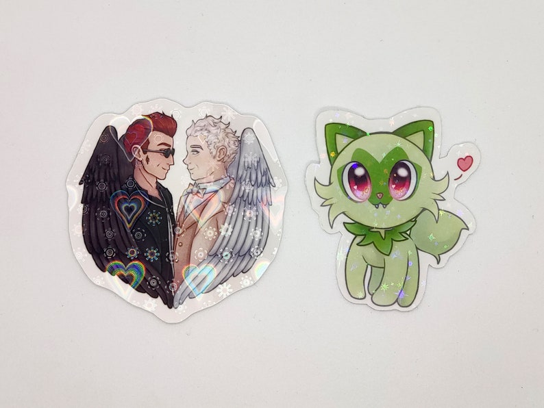 May include: Two cartoon characters, one with black wings and the other with white wings, are standing side-by-side. They are both smiling and looking at each other. The background is a heart shape with rainbow hearts and stars. A green cartoon character with big eyes and a heart above its head is also shown.