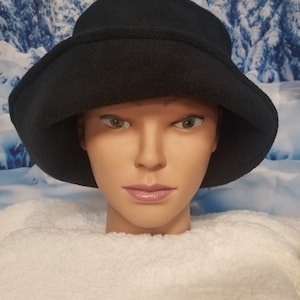 May include: A black fleece bucket hat with a wide brim. The hat is soft and warm, perfect for cold weather.