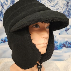 May include: A black fleece hat with ear flaps and a brim. The hat has a drawstring at the back.