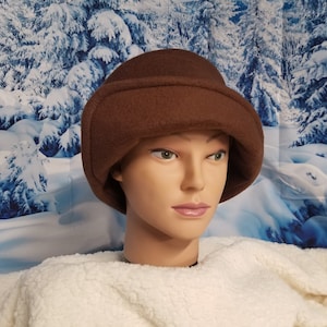 May include: A brown fleece hat with a wide brim and a soft, plush lining. The hat is designed to cover the ears and neck for warmth.