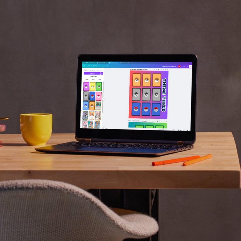 May include: A laptop computer displaying a website with a colorful grid of images. The grid is labeled "Theme Three". The laptop is on a wooden desk with a yellow mug and two orange pens.