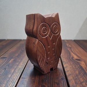 May include: A handcrafted wooden owl figurine with intricate carved details. The owl is a warm brown color and features detailed eyes and feather patterns. The figurine is a decorative item, likely for home decor.