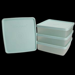 May include: A set of four square, light blue Tupperware containers with matching lids. One lid is off to the side, revealing the brand name and logo. The containers are stacked, showcasing their shape and design. The containers are made of plastic.