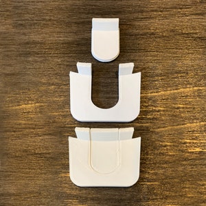 Puede incluir: Tres piezas de plástico blanco que encajan para crear un soporte en forma de U.