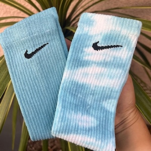 Puede incluir: Un par de calcetines de color azul y blanco con un logotipo de Nike negro en forma de swoosh en cada calcetín.