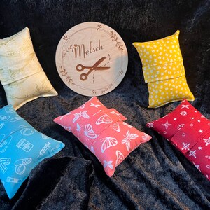 Könnte beinhalten: Sechs kleine Stoffbeutel mit verschiedenen Mustern. Die Beutel sind aus Baumwolle und haben eine Klappe, die mit einem Knopf verschlossen wird. Die Beutel sind in einem Kreis auf einer schwarzen Oberfläche angeordnet. Die Beutel sind alle in verschiedenen Farben und Mustern. Die Beutel sind alle etwa 25 cm lang und 12,5 cm breit. Die Beutel sind perfekt zum Verstauen von kleinen Gegenständen wie Schmuck, Münzen oder Schlüsseln.