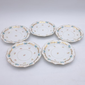 Puede incluir: Cinco platillos de porcelana blanca con bordes festoneados. Cada platillo presenta un borde dorado, detalles florales azules y pequeños detalles de flores rojas. Un diseño clásico y elegante.