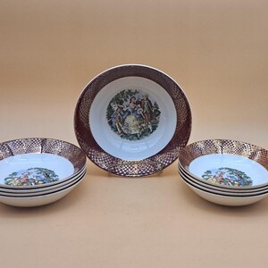 May include: A set of vintage porcelain bowls with a decorative design. The bowls have a white interior with a colorful scene, a brown and gold rim, and a black trim. One larger bowl stands behind two stacks of smaller bowls.
