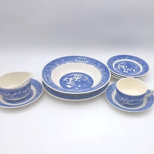 May include: A blue and white ceramic tableware set, comprising a large bowl, saucers, plates, a creamer, and a teacup. The pieces display a detailed blue pattern on a white background. The set is arranged on a white surface.