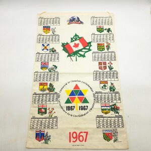 以下が含まれることがあります： 1967年の白い布製壁掛けカレンダー。カナダ連邦結成100周年記念ロゴ、カエデの葉の上に描かれたカナダ国旗、ビーバーのイラスト、そして各州の紋章が添えられた12ヶ月分のカレンダーグリッドがデザインされています。