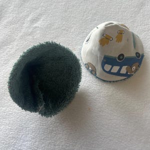 Può includere: Due coperture per biberon. Una è verde scuro e soffice. L'altra è bianca con un motivo di autobus e orsi blu. Le coperture sono progettate per adattarsi ai biberon.