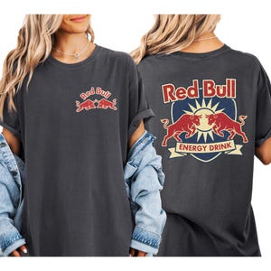 a woman wearing a grey t-shirt with the Red Bull logo and a graphic of two bulls.