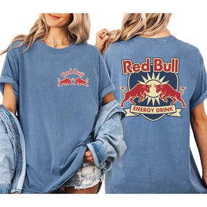 A woman wearing a blue t-shirt with the Red Bull logo and a graphic of two red bulls.