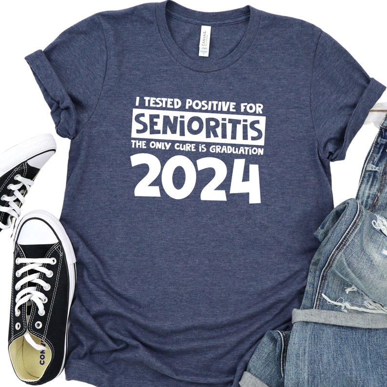 Op de afbeelding: Een marineblauw T-shirt met witte tekst die luidt: "Ik ben positief getest op Senioritis. De enige remedie is afstuderen in 2024".
